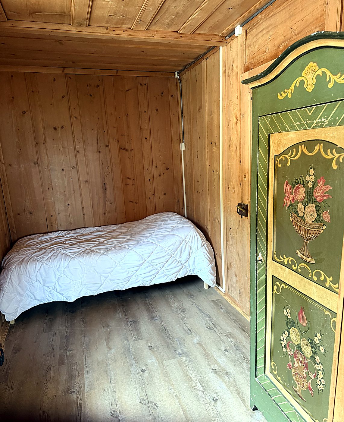 Chambre avec lit simple et armoire peinte à motifs floraux
