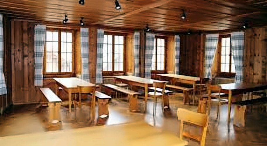 Grande salle lambrissée avec tables et bancs en bois