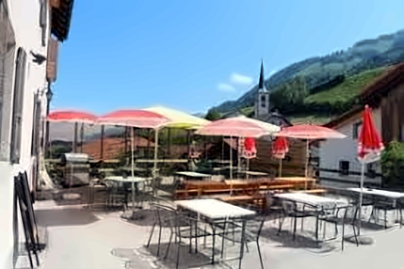 Terrasse avec parasols et vue sur l'église et les montagnes