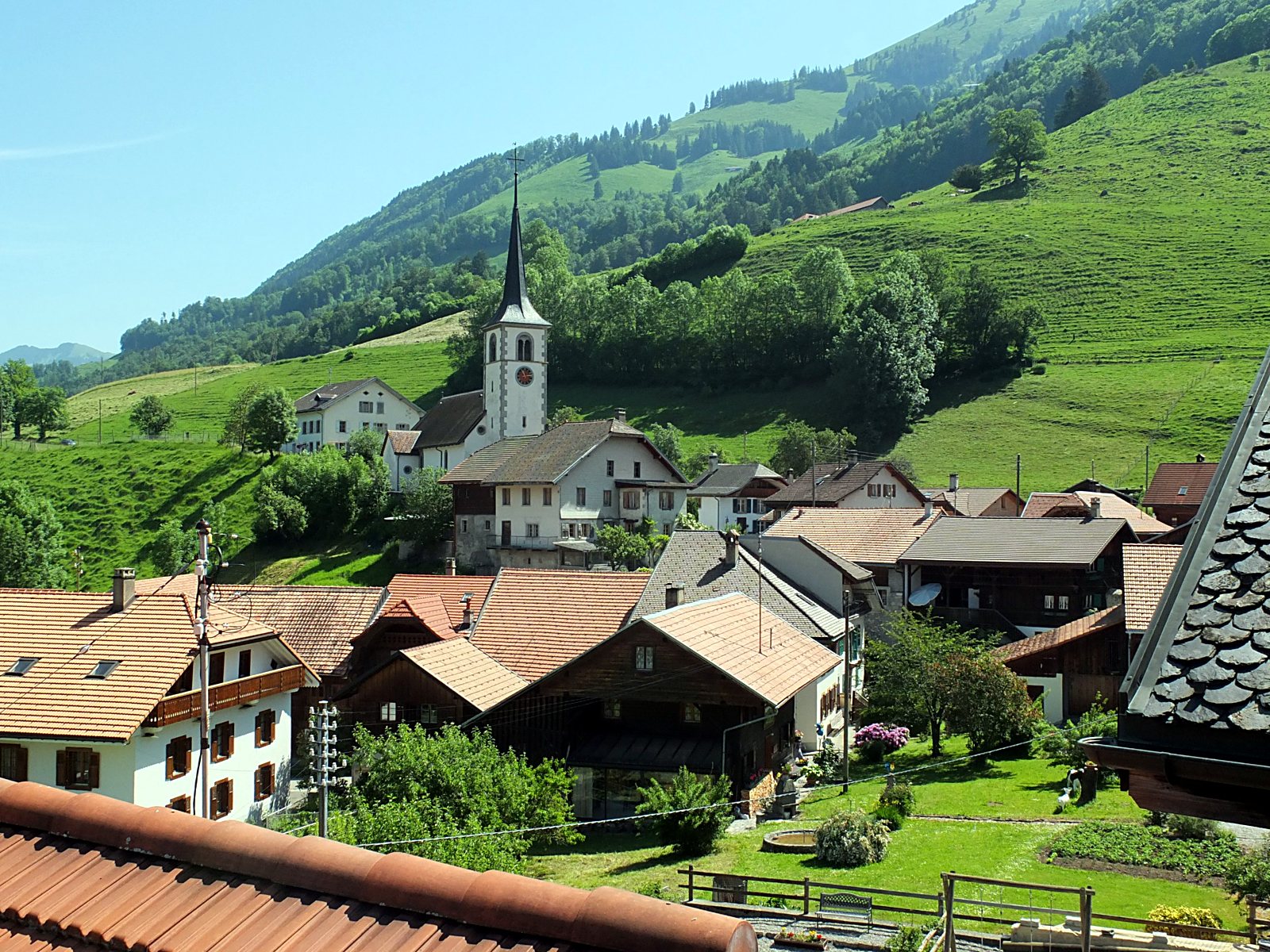 Les toits de Lessoc et le clocher de l'église Saint-Martin, au pied de pâturages verdoyants